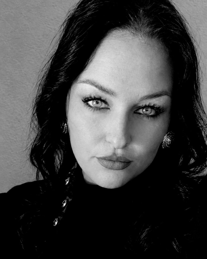 Black-and-white portrait of Fawn Elizabeth Zion in a black high-neck top and statement earrings